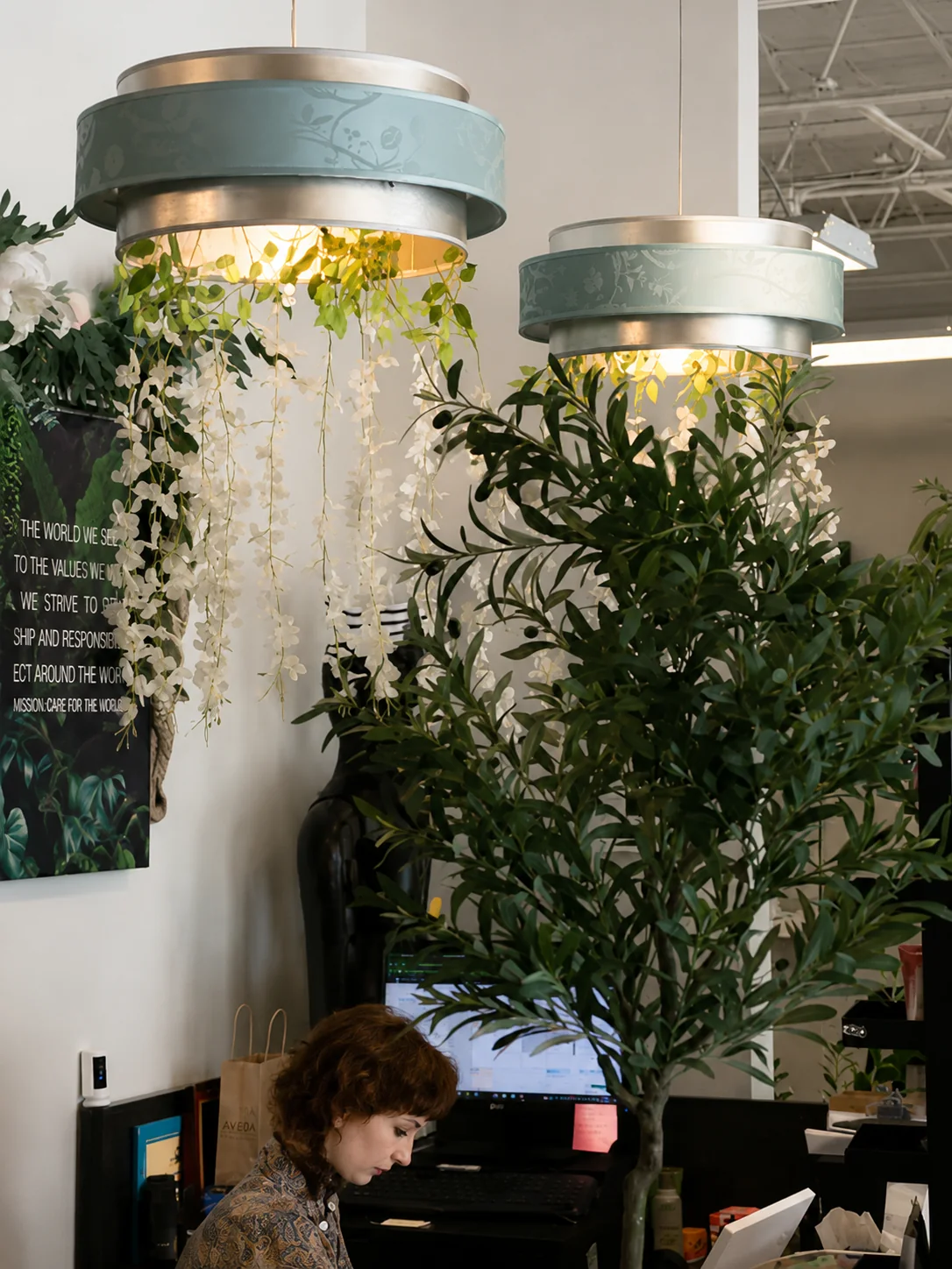 Interior of Aqua Aveda Salon & Spa with pendant lights and plants above the reception and work area